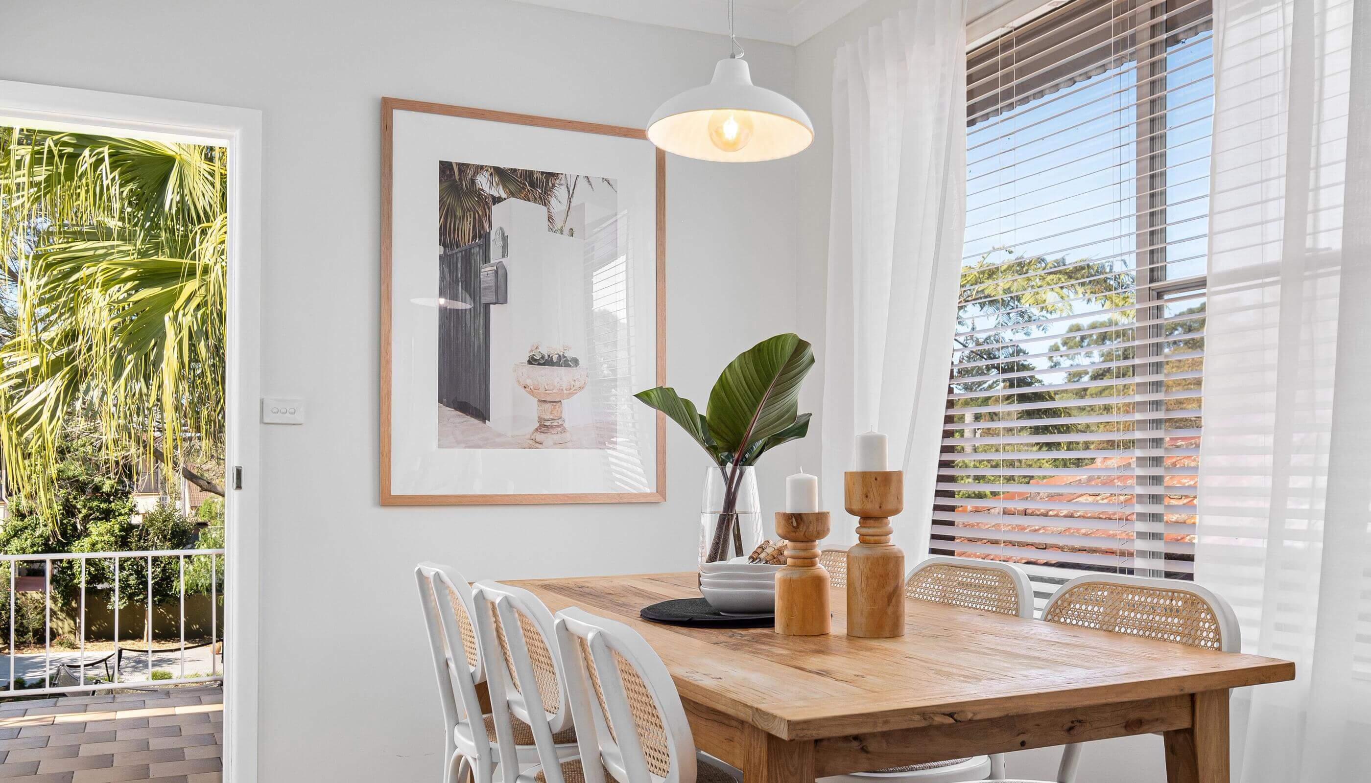 Bright dining area with a white pendant light, wooden table, and large windows letting in natural light