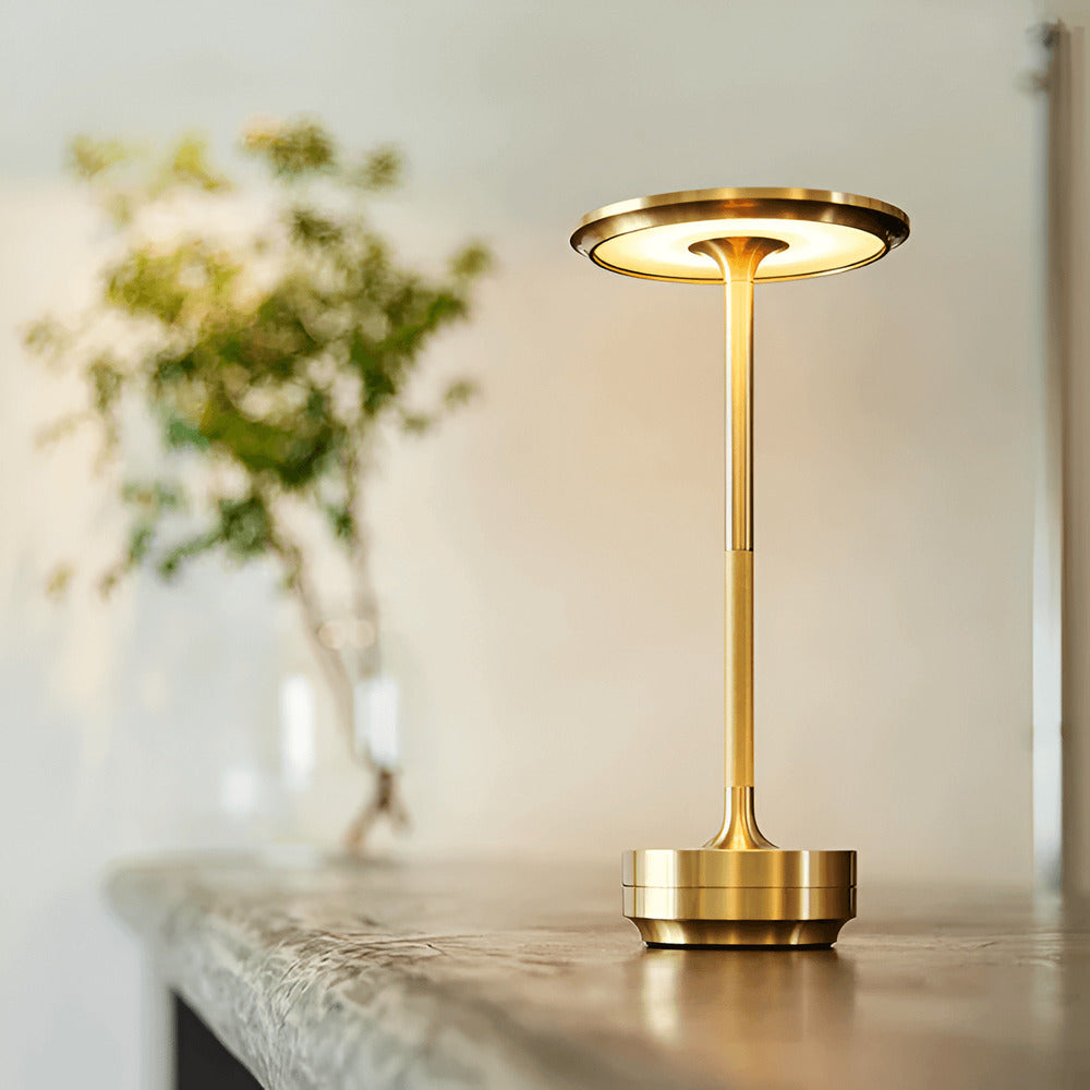 Gold cordless table lamp with soft LED lighting on a stone surface, ideal for modern interiors.