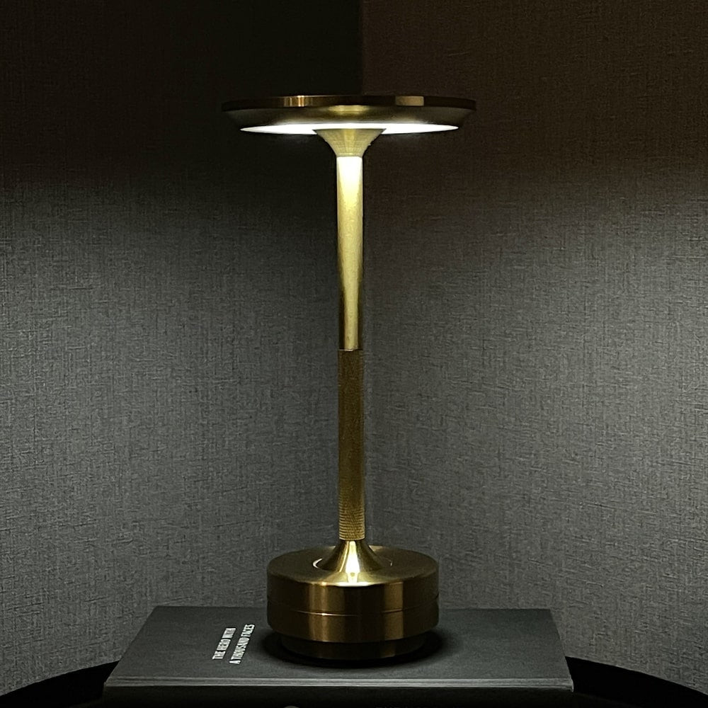 Elegant brass cordless table lamp on a book, creating a cozy reading atmosphere at night.