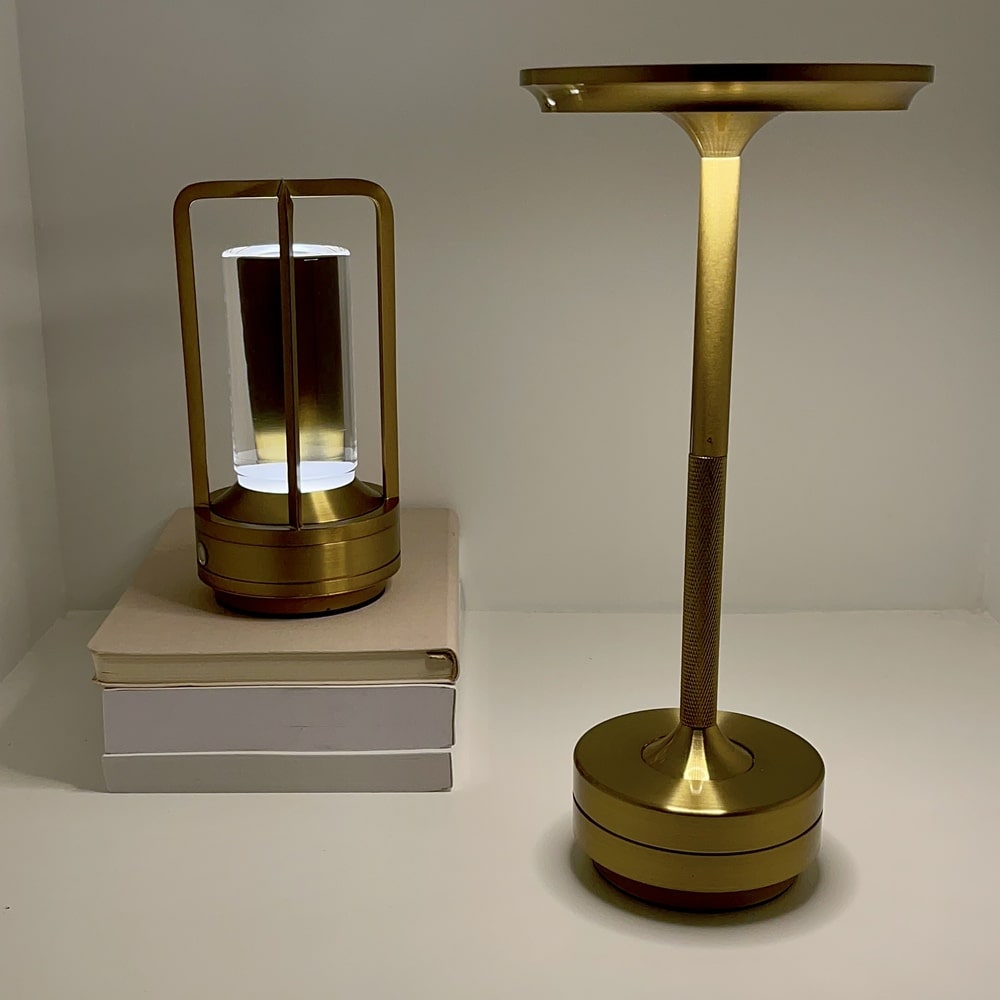 Brass cordless table lamp alongside a decorative companion light, both placed on a white desk.