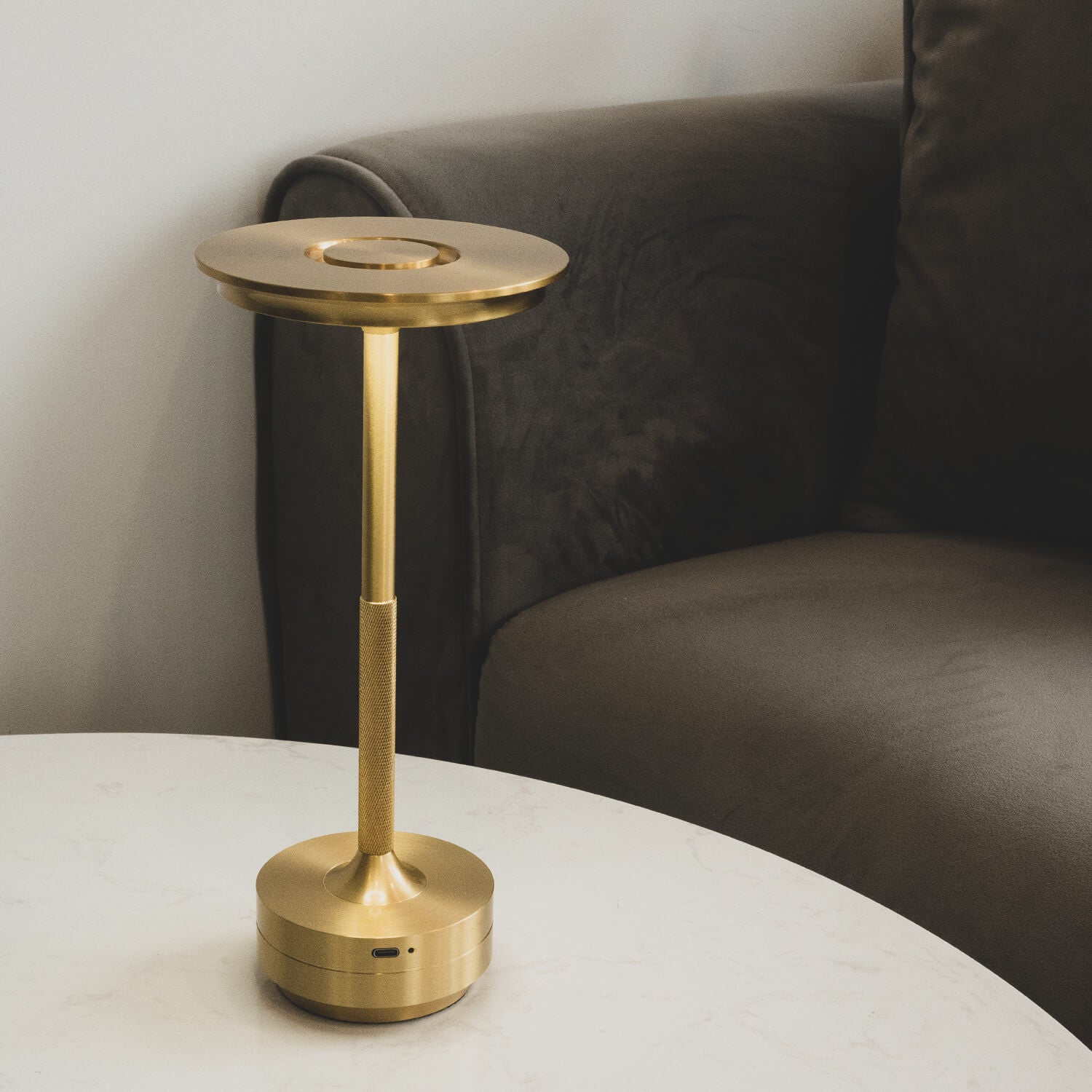 Cordless brass table lamp placed on a side table near a sofa, ideal for reading.