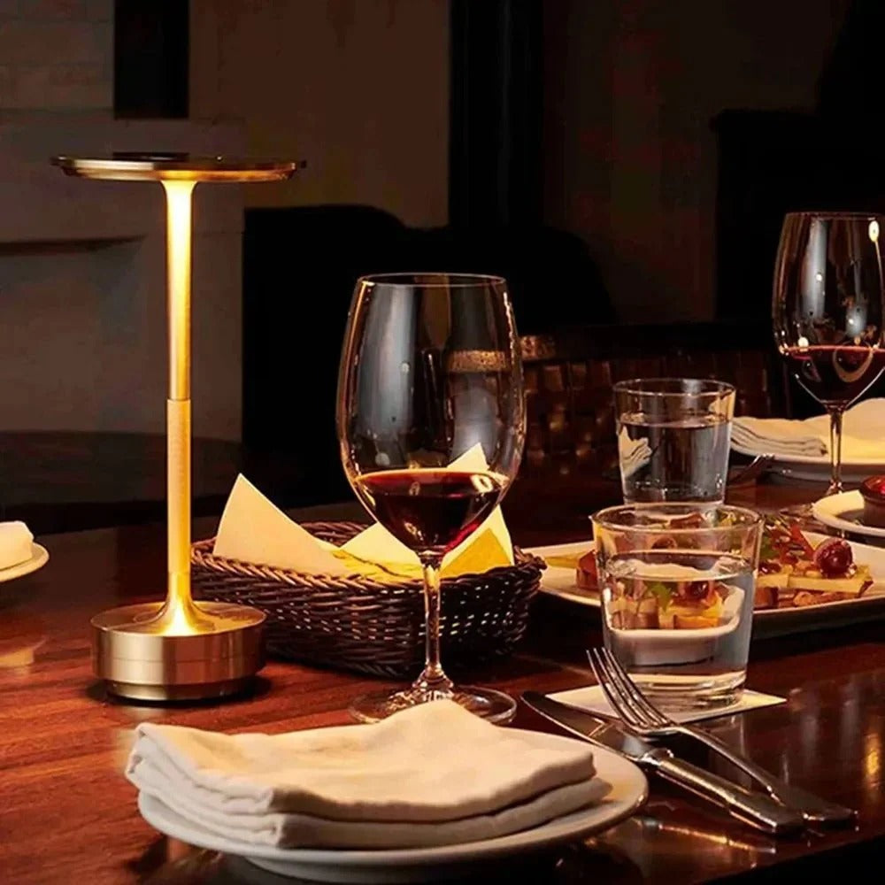 Brass cordless table lamp on a dining table, adding soft lighting to an elegant dinner setting.