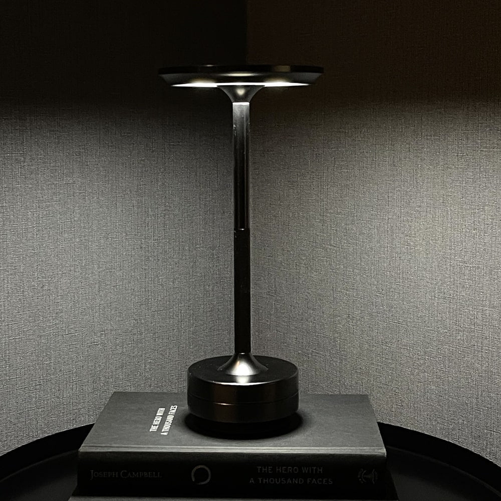 Cordless table lamp illuminating a book on a shelf, offering a sleek, minimalist design for modern spaces