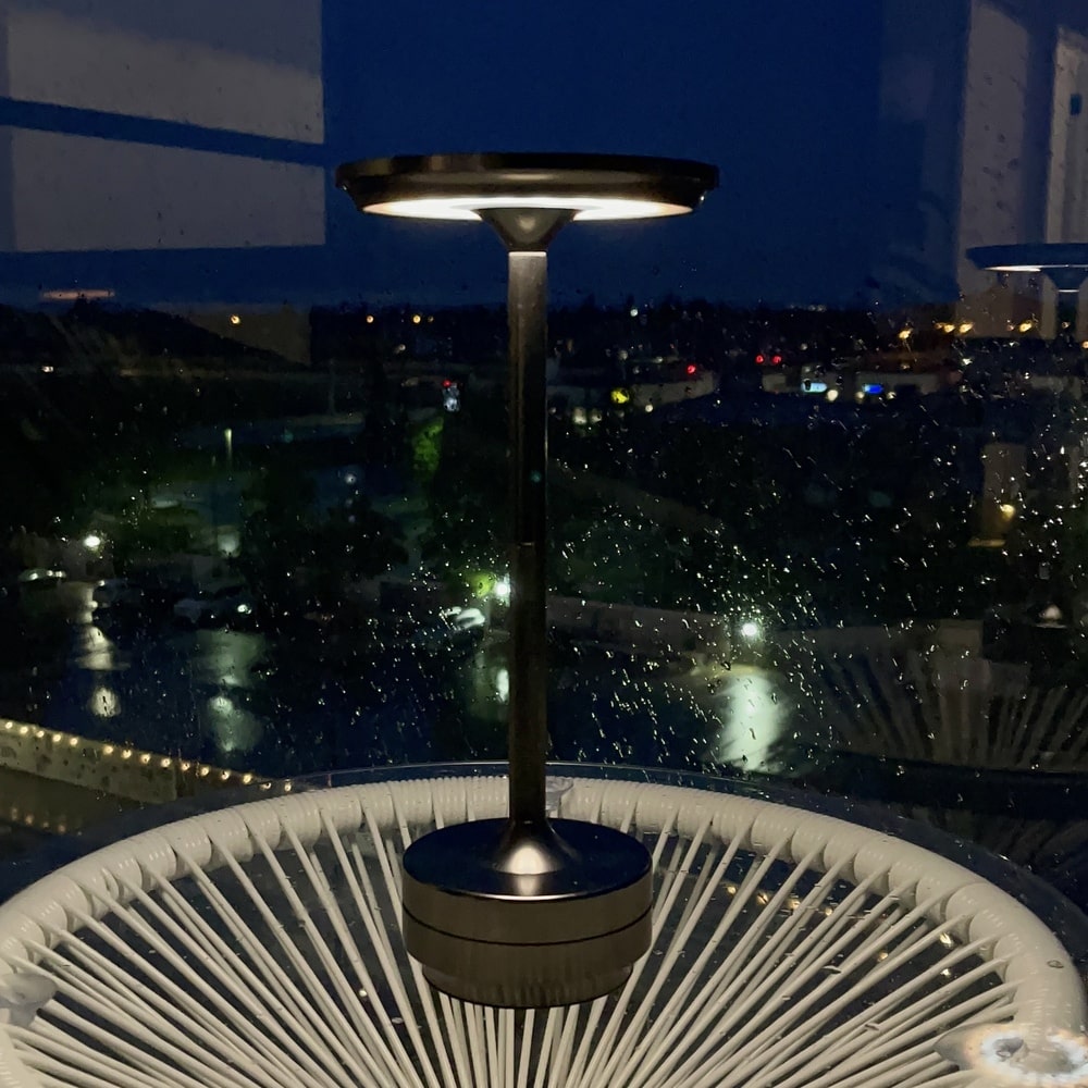 Sleek cordless table lamp by a window at night, creating a soft ambient light in a modern setting