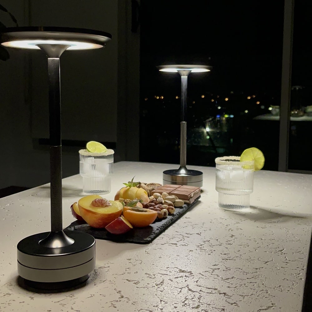 Cordless table lamp with rechargeable battery and modern design next to fresh fruits and drinks on a dining table