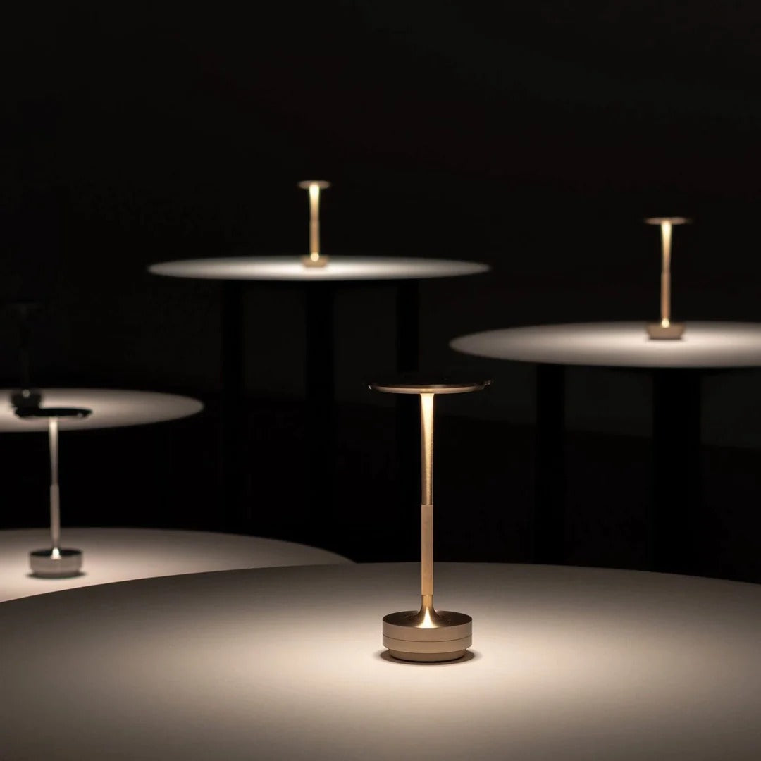 Portable cordless table lamps in a dark room with minimalist round tables and ambient lighting