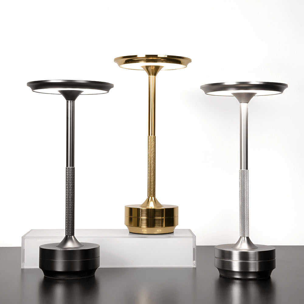 Three cordless table lamps in gold, black, and silver finishes displayed on a white background.