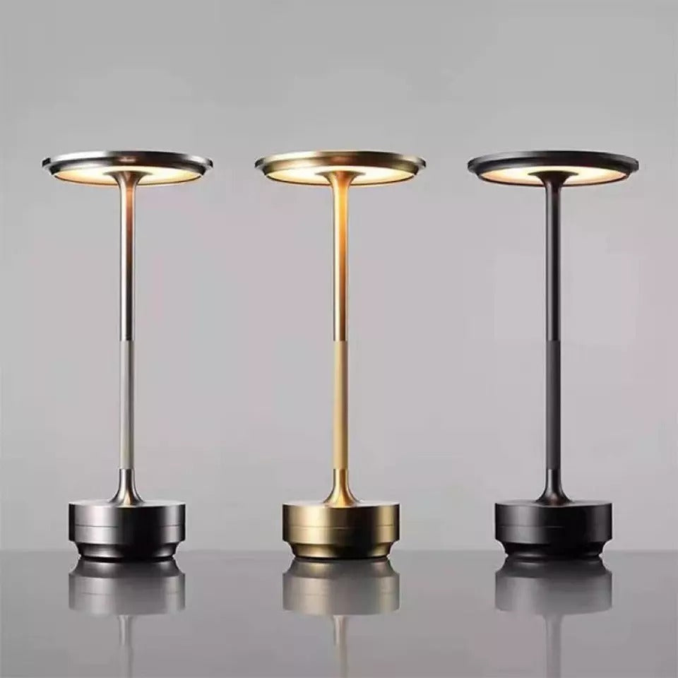 A set of three cordless table lamps in different metallic finishes: silver, gold, and black, with a sleek design.