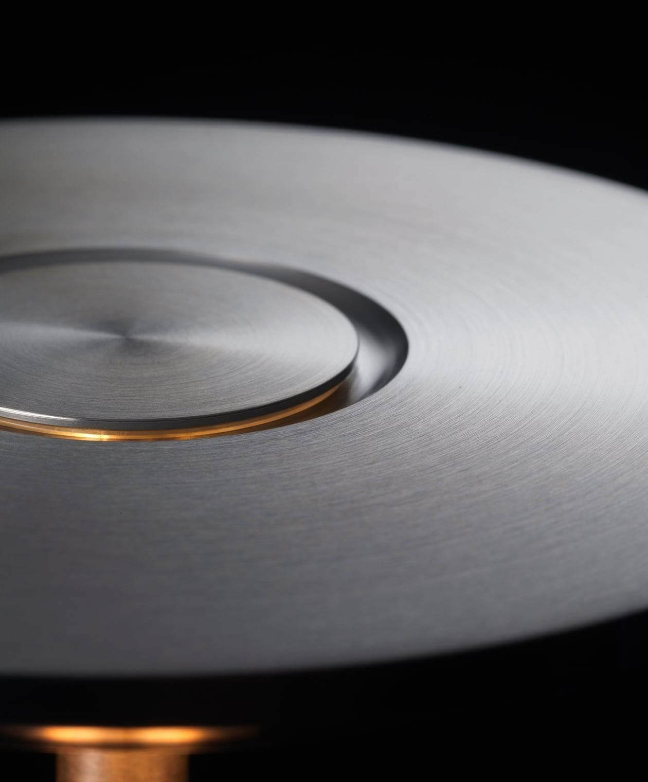 Close-up of the brushed metal surface of a modern cordless table lamp, showcasing its smooth and sleek texture.