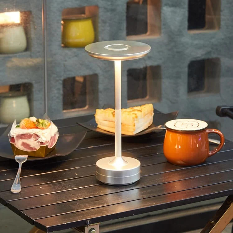 Rechargeable portable table lamp on a dining table, providing ambient lighting, perfect for restaurants or cafes.