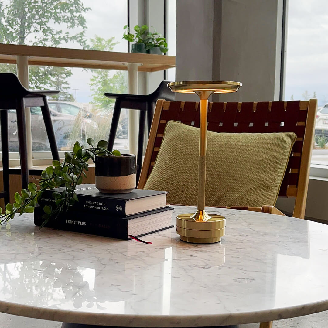 Elegant cordless table lamp in brass on a marble coffee table in a modern living room.