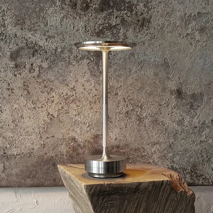 Cordless rechargeable metal table lamp with minimalist design, set on a rustic wooden surface.
