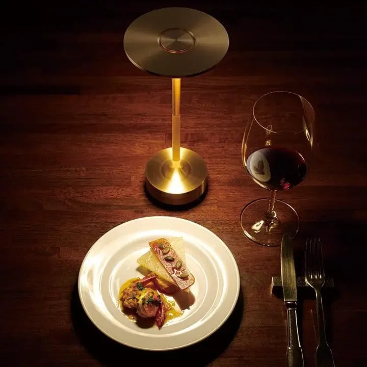 Elegant brass cordless table lamp lighting a dinner setting, perfect for intimate dining and restaurants.