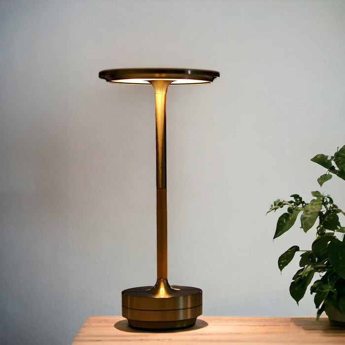 Brass cordless rechargeable table lamp on a wooden surface, modern design for home or office use.