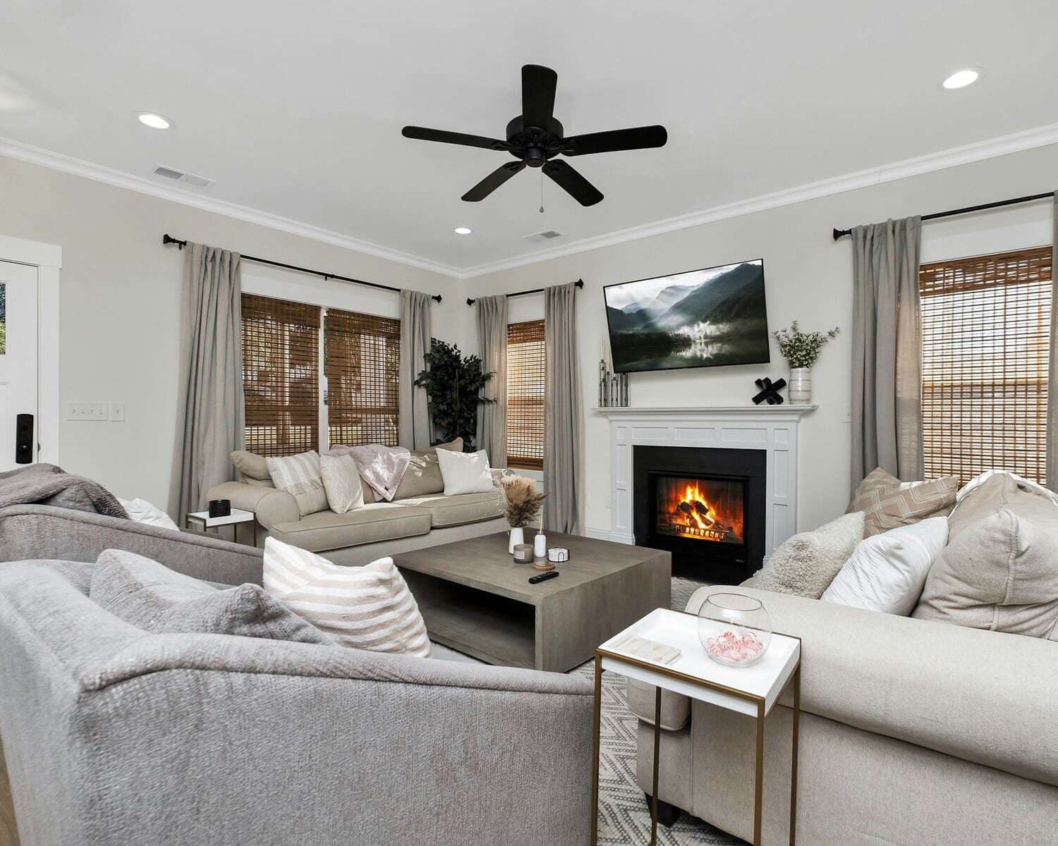 Black ceiling fan in a cozy living room with a fireplace, neutral sofas, and modern decor accents.