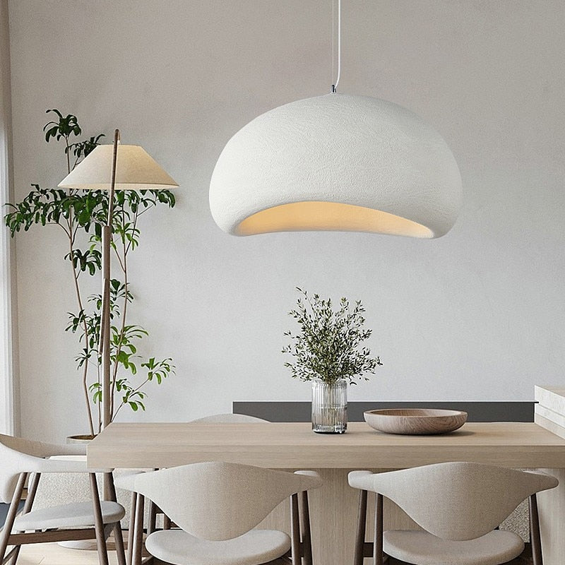 Minimalist chandelier hanging over a dining table, creating a serene ambiance in the dining area.