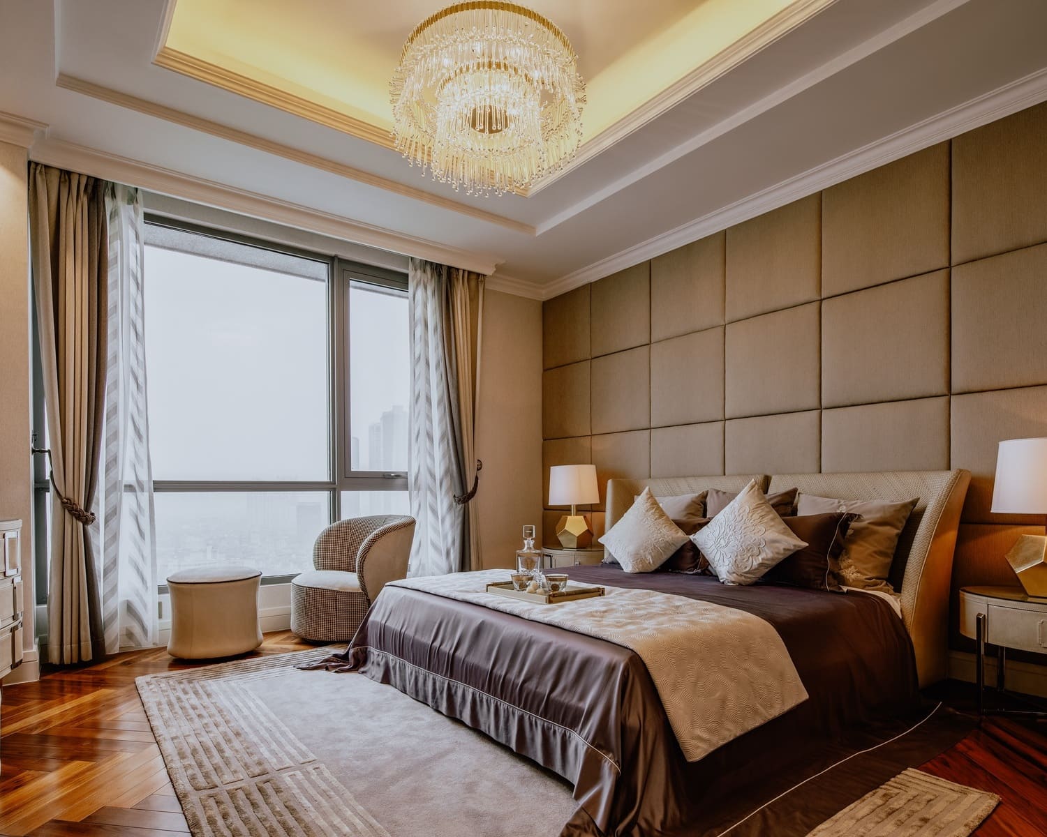 Elegant modern bedroom featuring a crystal chandelier and large window with sheer curtains.