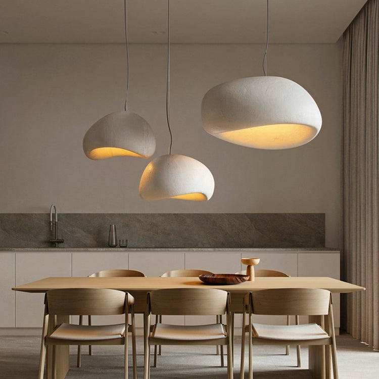 Group of wabi-sabi pendant lamps hanging in a modern dining area, creating a cozy and warm atmosphere.